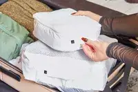 Hands placing packing cubes inside the July Checked Plus Large Luggage