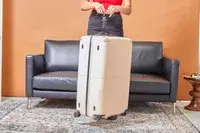 A person weighs the July Checked Plus Large Luggage