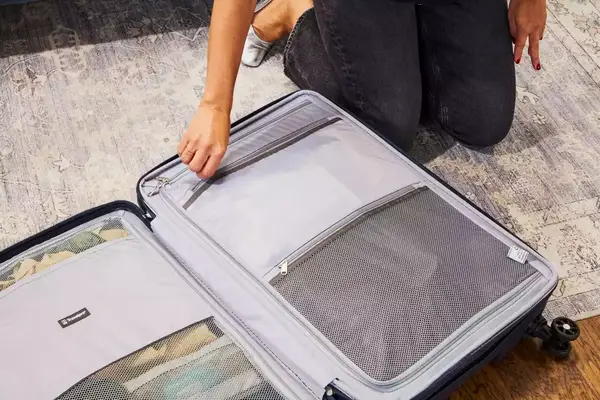 Person zipping a pocket in the Travelpro Maxlite Air Medium Check-In Hardside Spinner
