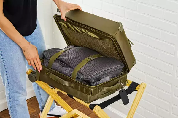 A person opening a packed Dagne Doverr Seattle Carry On Rolling Luggage 20.5