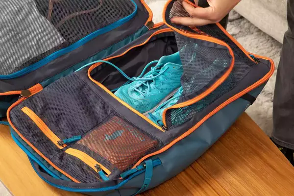 Hand holding a mesh flap on the inside of the Cotopaxi Allpa 35L Travel Pack