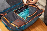 Hand holding a mesh flap on the inside of the Cotopaxi Allpa 35L Travel Pack