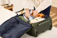 A person places travel items into the Lipault Foldable Plume Cabin