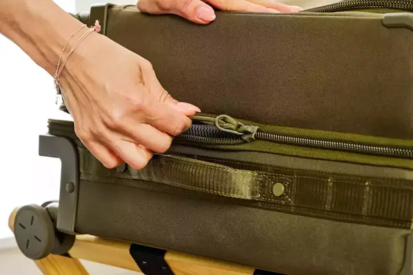 A person zippering the Dagne Doverr Seattle Carry On Rolling Luggage 20.5