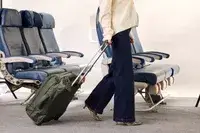 A person wheels the Lipault Foldable Plume Cabin over carpet