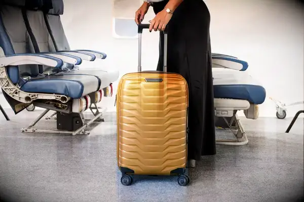 A person wheeling the Samsonite Proxis Global Carry-On Spinner down a plane aisle