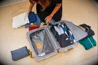A person packing a Tumi suitcase