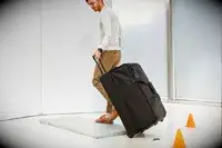 A man rolling a Tumi wheeled duffel