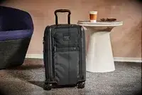 A Tumi suitcase in front of a table
