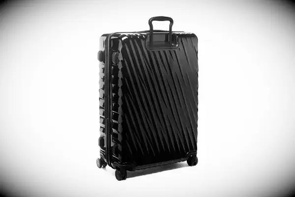 A person wheels the Samsonite Freeform 2-Piece Hardside Luggage Set over paving stones