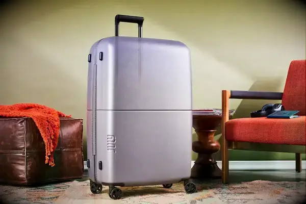 July Checked Plus Light suitcase next to a chair and table