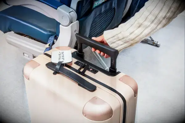 A person rolling a July suitcase on a plane