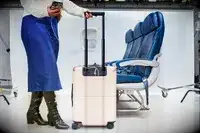 Person with their phone plugged into the July Carry On next to airplane seats