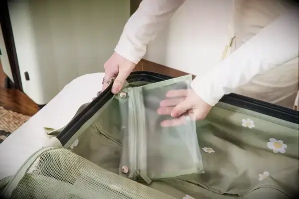 A person places a small zippered bag into the Calpak Evry Starter Bundle