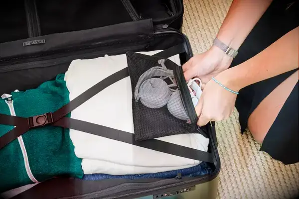 A person packing a Calpak suitcase