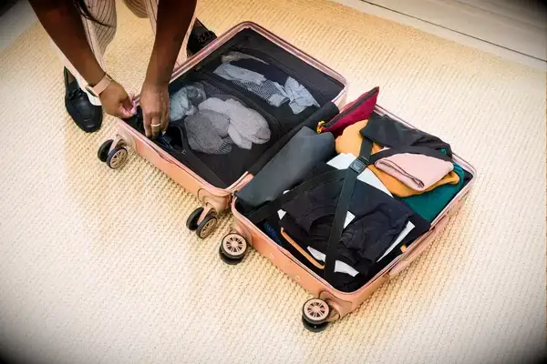 A person packing a Calpak suitcase
