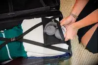 A person packing a Calpak suitcase