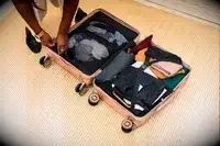 A person packing a Calpak suitcase