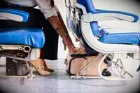 A person placing a Calpak underseater underneath an airplane seat