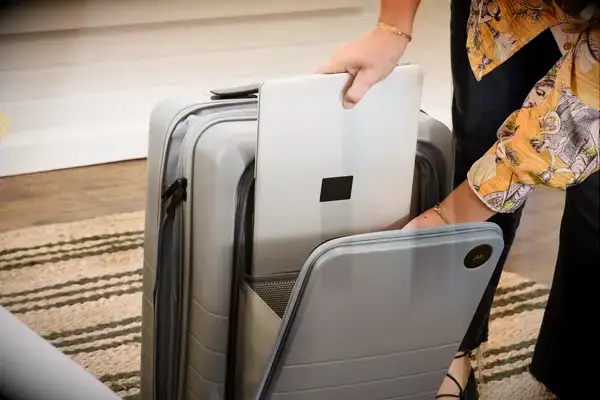 A person places a laptop into the Monos Expandable Carry-on Pro