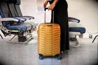 A person wheeling the Samsonite Proxis Global Carry-On Spinner down a plane aisle