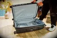 A person opening an empty suitcase Samsonite Outline Pro Large Spinner