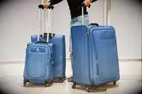 A person wheels the Travelpro Maxlite 5 Floating On Air Luggage set over paving stones