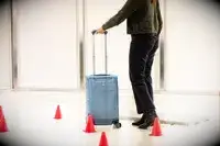 A person rolling a Travelpro Carry-on through an obstacle course of cones