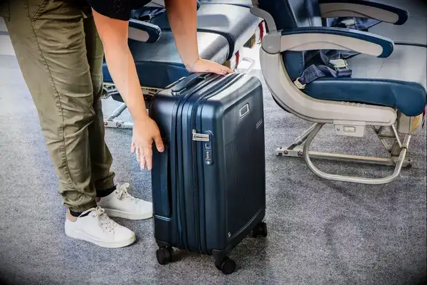 A person with a Briggs & Riley Essential 22-inch Carry-on on an airplane