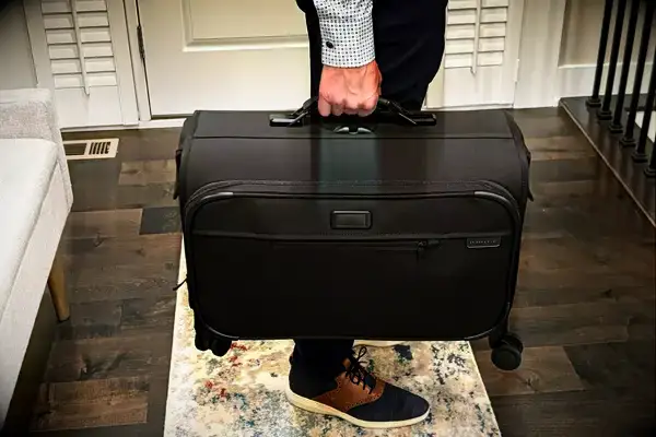 A man holding a Briggs & Riley garment bag suitcase
