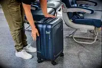 A person with a Briggs & Riley Essential 22-inch Carry-on on an airplane