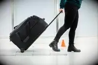 A person rolling a Briggs & Riley duffel with wheels