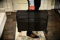 A man holding a Briggs & Riley garment bag suitcase