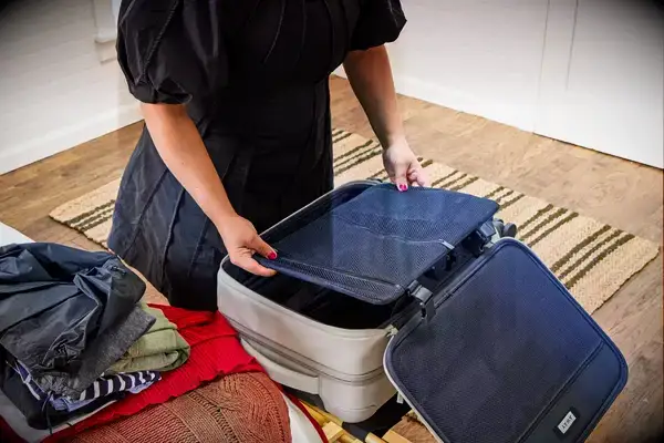 A person places items into the Away The Softside Carry-On