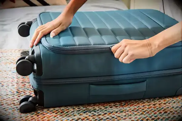 A person zips the Away Softside Bigger Carry-on