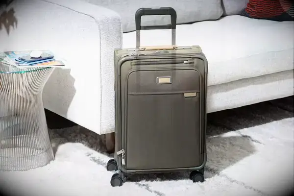 A person rolls the Samsonite Uplift Hardside Carry-on over a rug