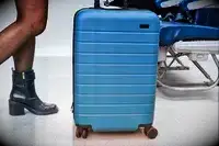 A person rolling an Away suitcase on a plane