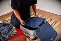 A person places items into the Away The Softside Carry-On
