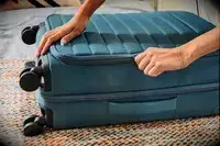 A person zips the Away Softside Bigger Carry-on