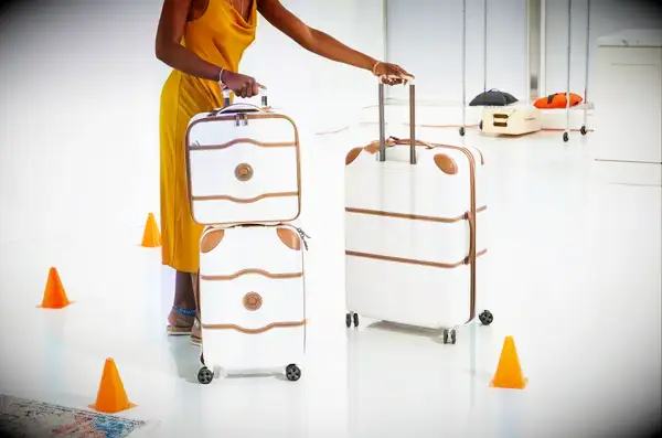 A person rolling a set of three Delsey suitcases