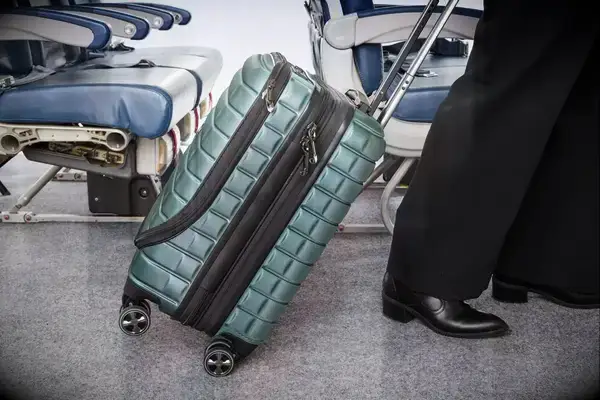 A person wheels the Delsey Paris Shadow 5.0 Carry-on with Laptop Compartment over carpet