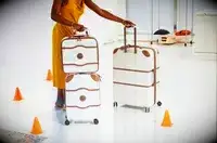 A person rolling a set of three Delsey suitcases