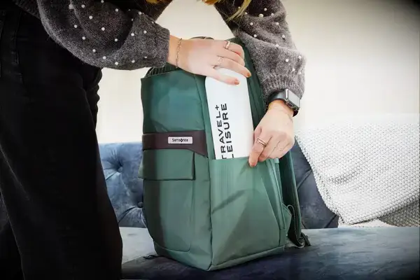 A person placing a water bottle in the Samsonite Elevation Plus Backpack
