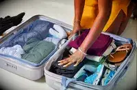 Two hands putting clothing into the Delsey Paris Cruise 3.0 24 Inch Medium Checked Spinner