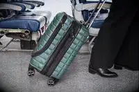 A person wheels the Delsey Paris Shadow 5.0 Carry-on with Laptop Compartment over carpet