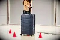 A person rolling a large Delsey suitcase