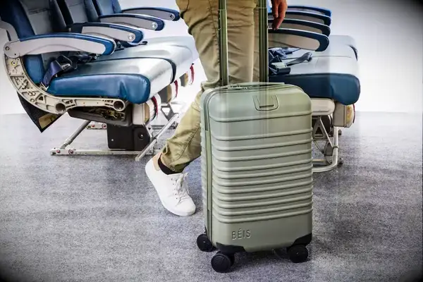 A person wheels the Béis The Small Carry-on Roller on carpet
