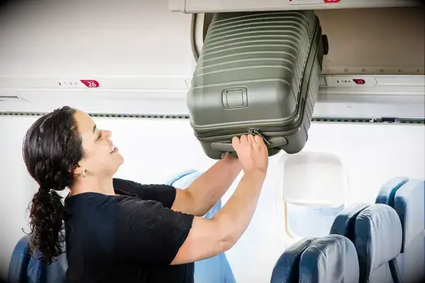 A person places the Béis The Small Carry-on Roller into an overhead compartment