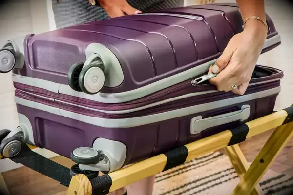 A person unzips the Samsonite 21 Inch Freeform Hardside Expandable Carry-on Spinner