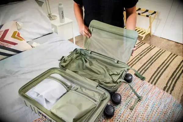 A person places a laptop pouch into the Béis The Small Carry-on Roller